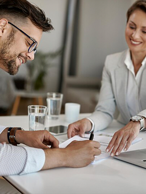 woman signing on white printer paper beside woman about to touch the documents